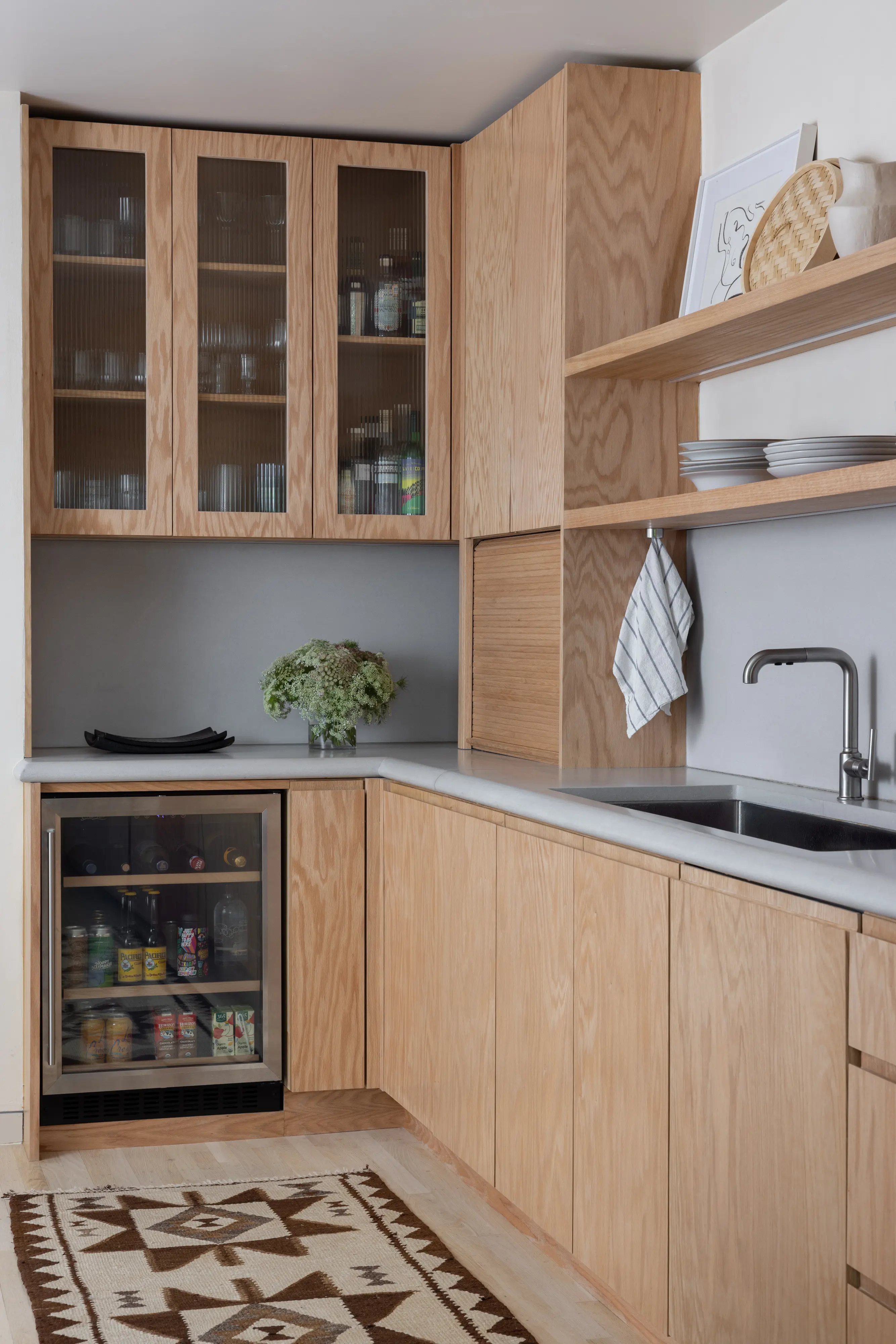 Kitchen bar area with reeded glass-front upper cabinets, beverage fridge, and concrete countertops in Parnassus Heights home designed by Studio VAE.